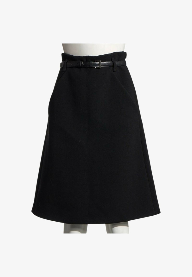 Jupe noire longueur genou en A avec une fine ceinture en cuir noir à la taille d'un mannequin blanc sur fond blanc.