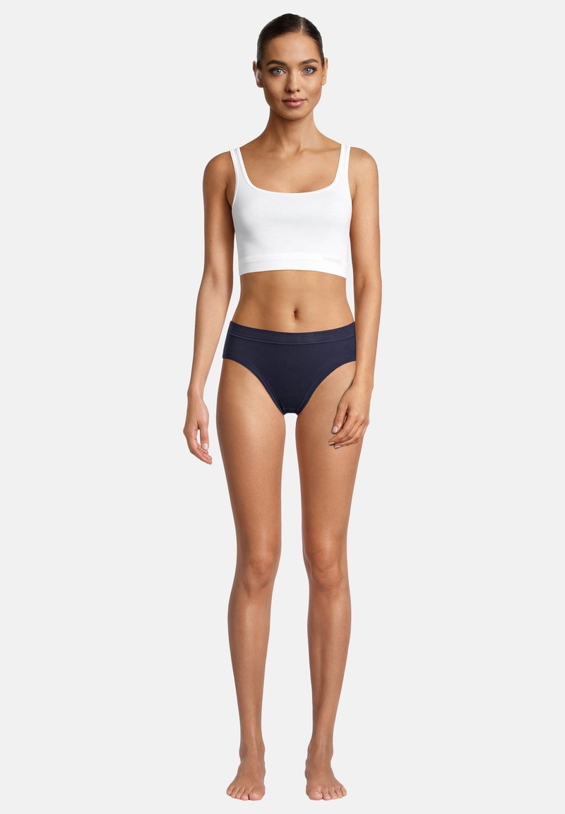 Weißes Baumwoll-Crop-Top mit breiten Trägern, kombiniert mit marineblauen, hochgeschnittenen Bikini-Höschen, beide aus einem glatten Material mit minimalistischem Design.
