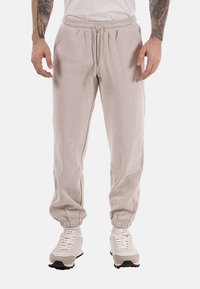 Pantalones jogger de pana beige con un corte relajado, cinturilla elástica, cierre con cordones y puños ajustados para un diseño cómodo y casual.