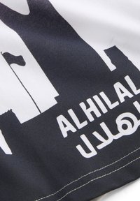Tela en blanco y negro con un diseño gráfico audaz que presenta la palabra "AL HILAL" en blanco, sobre un fondo contrastante.