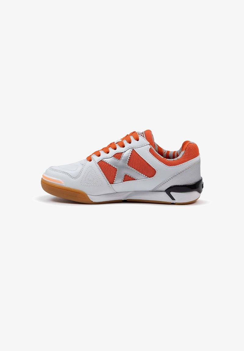 Zapatilla deportiva blanca con acentos naranjas, que presenta una parte superior de malla, suela de goma y un distintivo logo gris en el lateral.