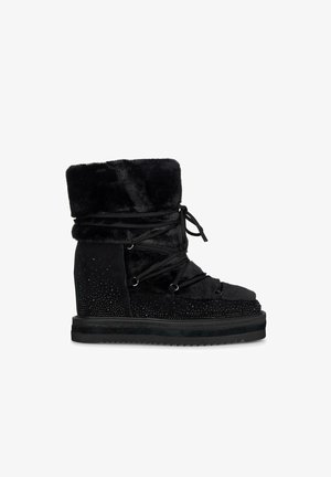 Black, fur-lined ankle boot with lace-up front, accented with rhinestones on the side, featuring a textured suede finish and rubber sole.