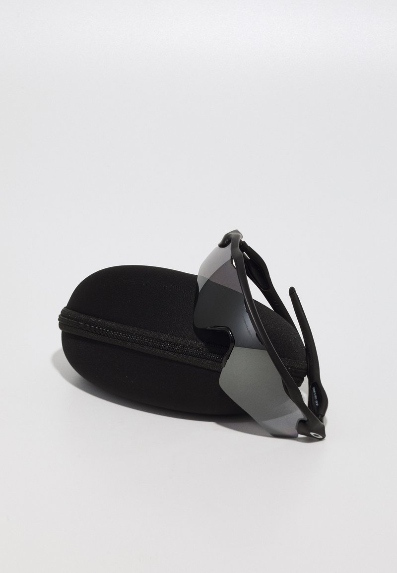 Black sunglasses with a wraparound design resting on a black zippered carrying case. Lenses are dark with a reflective finish.
