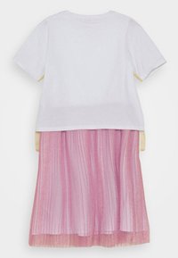 Haut blanc à manches courtes avec une jupe plissée rose ornée de paillettes. La jupe est superposée et légèrement plus longue que le haut.