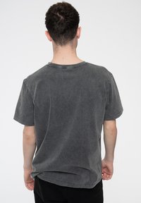 Gray cotton short-sleeve T-shirt with a classic round neck and a faded texture. Features a relaxed fit and visible stitching details.