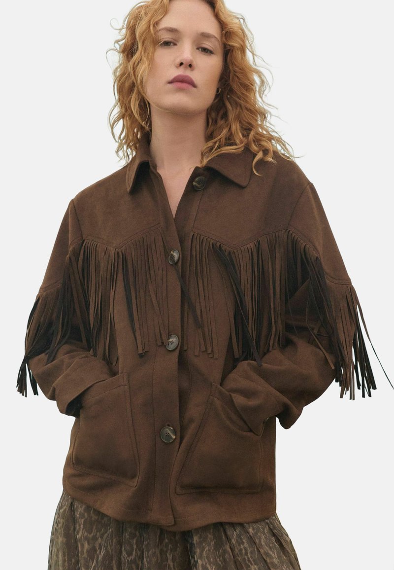 Brown suede jacket featuring front pockets, button closures, and fringe detailing along the sleeves and shoulders.
