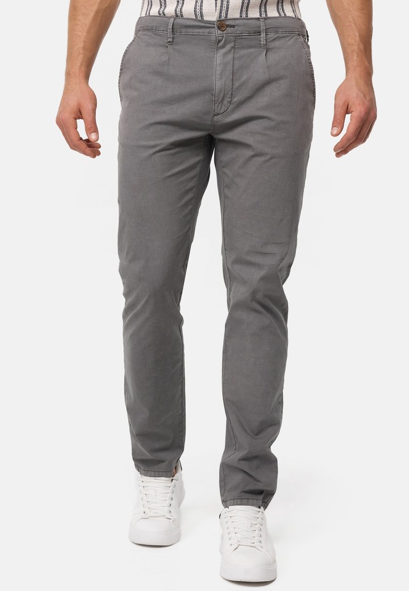 Grijze katoenen chino's met een slanke pasvorm, voorzien van steekzakken aan de voorkant, een knoopsluiting, gecombineerd met witte sneakers.