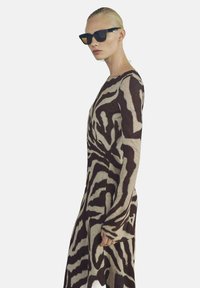 Long-sleeve sweater in brown and beige with a zebra print design. Made of soft material, features a relaxed fit and side slit details.