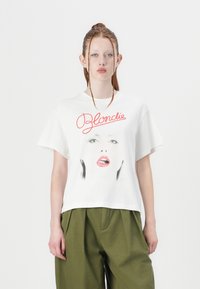 White cotton t-shirt featuring a graphic face print and red "Blondie" text. Relaxed fit with short sleeves and a crew neckline.