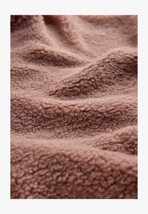 Material fleece texturat, pufos, de culoare roz pal, cu o suprafață unduitoare și ondulată, având un aspect ușor pufos.