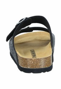 Black sandals with a cork sole, adjustable buckle, and contoured footbed. The upper has a soft texture with a minimalistic design.