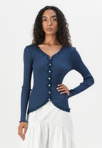 Cardigan long à manches longues côtelé marine avec une bordure en dentelle festonnée, plusieurs boutons sur le devant et un ourlet incurvé.