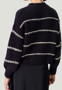Pull en maille bleu marine avec rayures blanches horizontales, présentant une finition texturée et une coupe décontractée. Manches longues avec poignets côtelés et col rond.