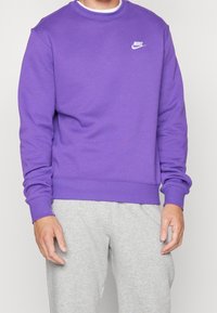 Lila sweatshirt i bomullsblandning, med rund halsringning, långa ärmar och en liten vit Nike-logotyp på bröstet.