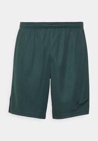 Pantalones cortos Nike en verde oscuro, hechos de tejido ligero. Cuentan con una cintura elástica, logo negro y una textura suave con ventilaciones laterales.