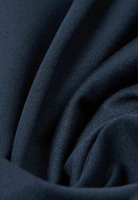 Tessuto blu navy scuro, texture morbida, finitura liscia, drappeggiato in pieghe che mettono in evidenza cuciture sottili e una ricca profondità di colore.