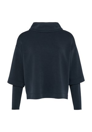 Haut surdimensionné bleu foncé avec un col montant, des manches courtes, et une couche ajustée en dessous. Texture douce avec des détails de couture minimaux.