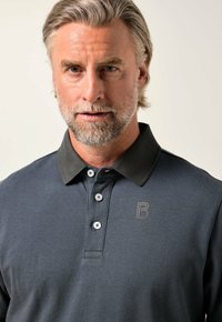 Námořnická polokošile s tmavě šedým límečkem, tříknoflíkovým zapínáním a nenápadným logem 'B' na hrudi. Texturovaná látka s hladkým povrchem.