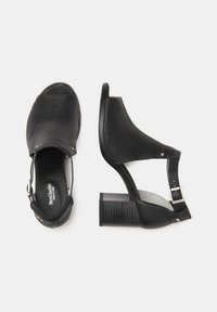 Black heeled sandals with a textured finish, open toe, adjustable ankle strap, and block heel. Features a smooth interior lining.