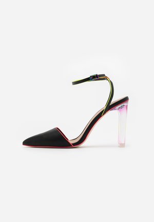 Czarny szpiczasty but na wysokim obcasie z przezroczystym akrylowym obcasem. Posiada różowy akcent na krawędzi oraz wielokolorowy pasek wokół kostki.