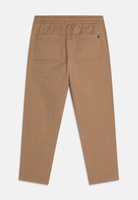 Brązowe bawełniane spodnie z elastycznym pasem, dwoma tylnymi kieszeniami i prostymi nogawkami. Gładka tekstura i minimalne detale szwów.