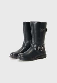 Botas de cuero negro hasta la rodilla con una textura suave, correa ajustable y detalle de hebilla, suela plana de goma y forma de punta ovalada.