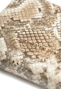 Clutch con estampado de serpiente en tonos beige y marrón, con texto dorado en relieve "ALMA EN PENA". Textura suave con un sutil brillo.