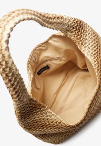 Vevd stråveske med beige stoffforing, med en glidelåslomme på innsiden og solide håndtak. Åpen design for enkel tilgang.