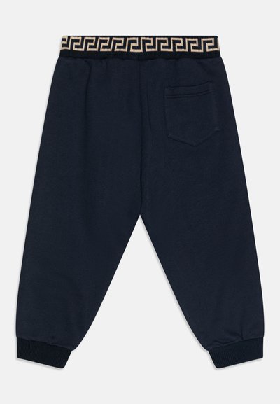 Jūras zila sporta bikses, izgatavotas no mīkstas auduma, ar rakstainu elastīgu jostasvietu un vienu aizmugurējo kabatu. Pabeidz dizainu ar izgrieztiem līkumiem.