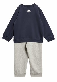 Felpa di colore blu con maniche lunghe e polsini a coste, abbinata a pantaloni della tuta grigi. Entrambi realizzati in materiale morbido; logo sul retro.