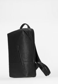 Zaino in pelle nera con forma rettangolare, spallacci imbottiti e regolabili, maniglia superiore e tasca frontale con zip. Finitura testurizzata e dettagli di branding.
