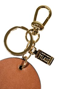 Portachiavi in metallo dorato e moschettone attaccati a un portachiavi in pelle marrone con un piccolo tag dorato etichettato "Villaggio".