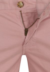 Rosa Baumwollhosen mit goldenen Reißverschluss und Knopfverschluss, sichtbar genäht und mit geradem Schnitt. Innenliegende Taschen sind ebenfalls vorhanden.