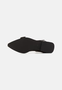 Zapato negro de tacón con punta afilada y parte superior texturizada. Cuenta con una sola correa a través del empeine y una suela lisa y plana. Talla 37.