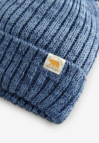Niebieska dzianinowa czapka beanie z prążkowanym wzorem, z podwiniętym brzegiem oraz kwadratową metką z pomarańczowym logo misia.