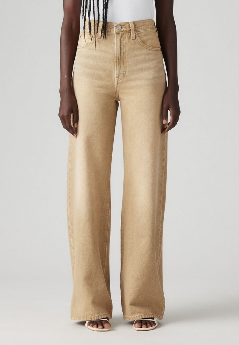 Jeans a gamba larga in denim beige chiaro con vita alta, caratterizzati da un classico design a cinque tasche e da una leggera sfumatura per aggiungere texture.