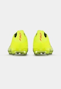 Φωτεινές κίτρινες ποδοσφαιρικές πατούσες με αεροδυναμικό σχεδιασμό, με διάφανο πάτο και το λογότυπο "F50" σε κόκκινο χρώμα στην φτέρνα.