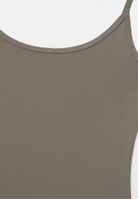 Gros plan sur un débardeur couleur taupe à fines bretelles avec une texture de tissu lisse et extensible.