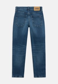 Tumed sinised teksad sirge säärega, mis on varustatud nahast brändi patch'iga taga ning kahe tagumise taskuga, millel on õmblustead.