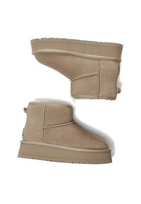 Beige Wildleder-Ankle-Boots mit einer strukturierten Oberfläche, kontrastierenden genähten Nähten, einem kurzen Absatz und einer Schlaufe hinten.