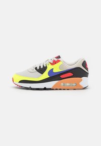 Nike Air Max-sneaker med en övre del av mesh och syntetmaterial i grått, neongula accenter, svarta överlägg, orange häl och synlig luftkudde.