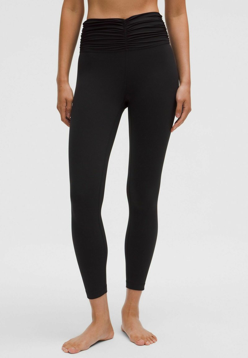 Fekete leggings rugalmas anyagból, begyűrt magas derékkal, testhez simuló formával és bokáig érő fazonnal. Az anyag sima tapintású.