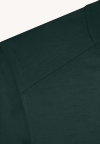 Chemise à manches courtes vert foncé avec une texture lisse, présentant une couture traversant l'épaule et un col côtelé.