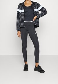 Svart jacka med vita prickar, svart linne och mönstrade leggings. Matcherades med svarta träningsskor.