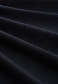 Donker marineblauwe stof met zachte plooien en zichtbare textuur, die het gladde en dichte geweven materiaal benadrukt.