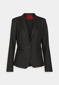 Blazer negro de mujer a medida con cierre de un solo botón, solapas con muesca y dos bolsillos frontales con abertura.