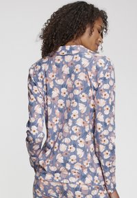 Dlhý rukáv kvetinová blúzka v svetlom odtieni modrej s bielymi a ružovými kvetmi. Vyznačuje sa jemnou, hladkou textúrou a golierom, navrhnutá pre pohodlie.