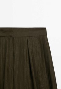 Jupe plissée vert olive foncé avec une texture lisse et une large ceinture, dotée de poches latérales et d'un léger éclat.