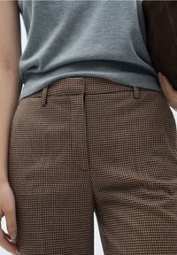 Pantalons à carreaux marron avec un petit motif, dotés d'un devant plat, de passants de ceinture et de poches latérales ; assortis à un pull gris.