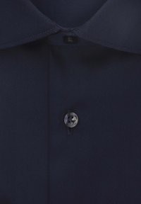 Camicia navy con bottoni, dal tessuto liscio, caratterizzata da un colletto classico e un singolo bottone nero davanti, vicino al collo.
